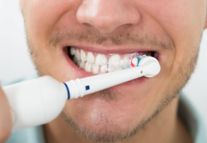Elektrisk tannbørste i munnen til en mann.
