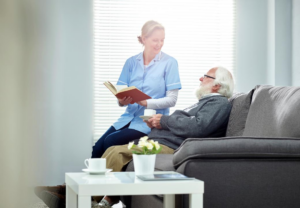 Helsemedarbeider sitter og snakker med en eldre mann.